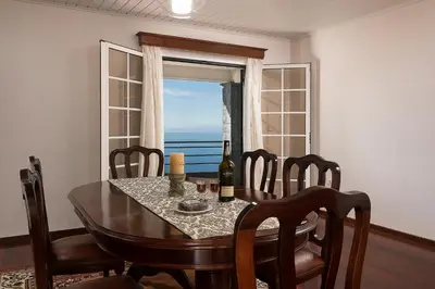 a dining room with a table and a window at Welcome home, with a fantastic view, sunrise & sunsets in Estreito da Calheta