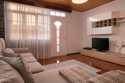 a living room with a couch and a tv at Welcome home, with a fantastic view, sunrise & sunsets in Estreito da Calheta