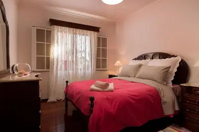 a bedroom with a large bed with a red blanket at Welcome home, with a fantastic view, sunrise & sunsets in Estreito da Calheta