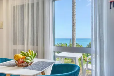 a room with a table and chairs and a view of the ocean at Quinta da Vila in Porto da Cruz