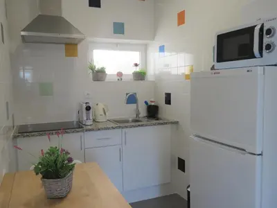 a small kitchen with a white refrigerator and a table at Sagres Relax Studios in Sagres