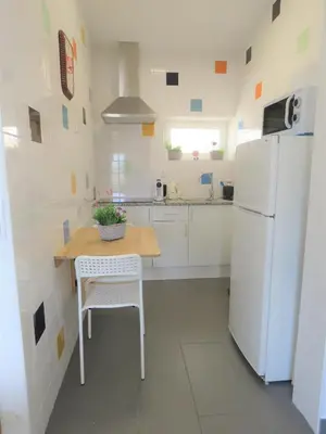 a kitchen with a table and a white refrigerator at Sagres Relax Studios in Sagres