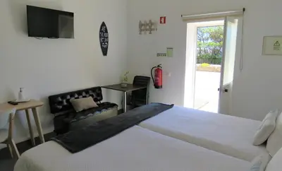 a bedroom with a bed and a chair and a television at Sagres Relax Studios in Sagres