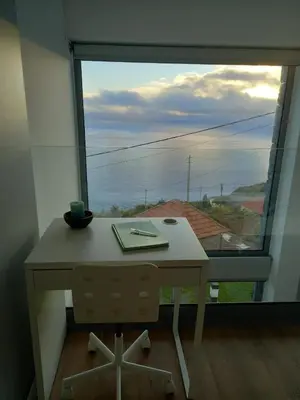 a desk in front of a window with a view at Refúgio de Pedra in Fajã da Ovelha