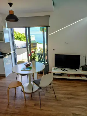 a living room with a table and chairs and a television at Refúgio de Pedra in Fajã da Ovelha