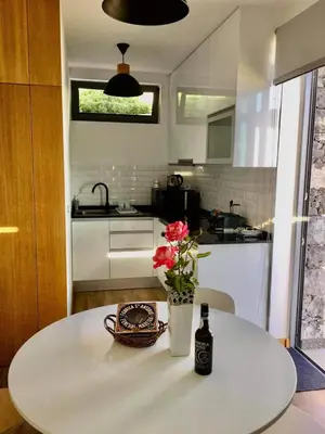 a table with a bottle of beer and flowers on it at Refúgio de Pedra in Fajã da Ovelha