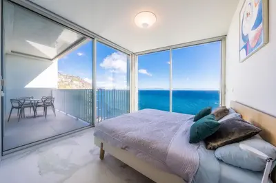 a bedroom with a bed and large glass windows at Barreirinha Front-Line Sea View II by Holiday Rental Madeira in Funchal