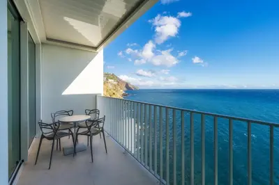 a balcony with chairs and a table and the ocean at Barreirinha Front-Line Sea View II by Holiday Rental Madeira in Funchal