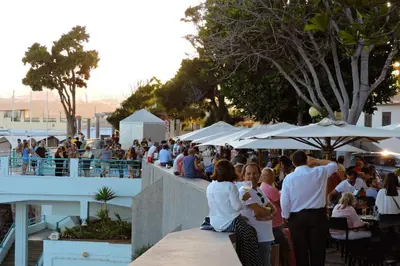 a crowd of people sitting at a restaurant with umbrellas at Barreirinha Front-Line Sea View II by Holiday Rental Madeira in Funchal