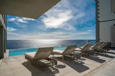 a row of chairs sitting on a patio overlooking the ocean at Barreirinha Suite Top Floor by Holiday Rental Madeira in Funchal