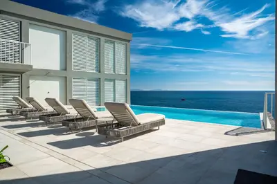 a row of lounge chairs on a patio with the ocean at Barreirinha Suite Top Floor by Holiday Rental Madeira in Funchal