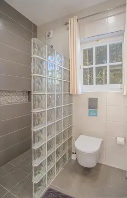 a bathroom with a toilet and a glass block wall at Casa Monte Cristo Tres in Lagos