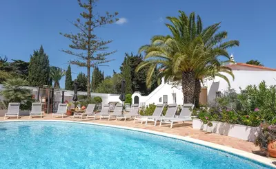 a swimming pool with lounge chairs and a palm tree at Casa Monte Cristo Tres in Lagos