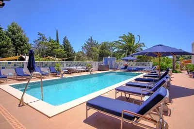 a swimming pool with lounge chairs and umbrellas at Casa Monte Cristo Apartments - Almond in Lagos