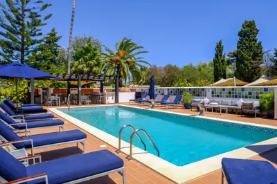 a swimming pool with lounge chairs and umbrellas at Casa Monte Cristo Apartments - Lemon in Lagos