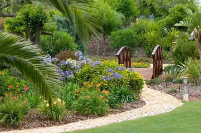 a garden with colorful flowers and a wooden path at Casa Monte Cristo Apartments - Plum in Lagos