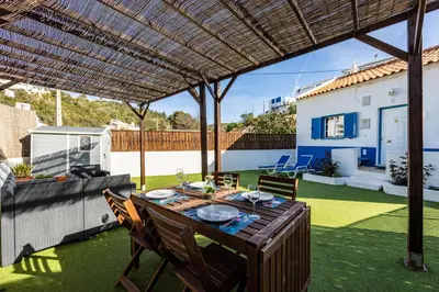 a patio with a table and chairs under a pergola at Salema Beach House in Salema