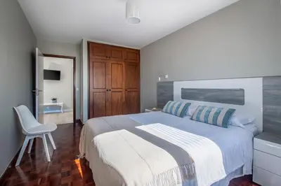 a bedroom with a large bed and a chair at ALEGRIA II in Funchal