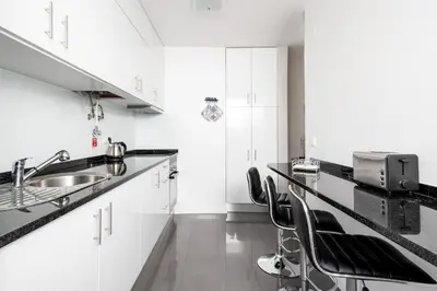 a kitchen with white cabinets and a sink and stools at ALEGRIA II in Funchal