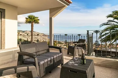 a balcony with a couch and a table with wine glasses at Exquisite Madeira Villa Villa Funchal Belair 4 Bedroom Panoramic Sea View in Funchal