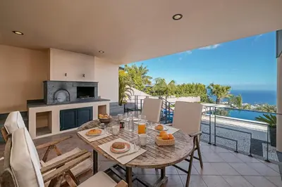 a dining room with a table and a view of the ocean at Exquisite Madeira Villa Villa Funchal Luz 5 Bedroom Heated Pool in Funchal