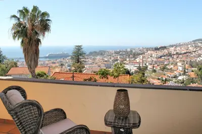 a balcony with chairs and a view of a city at Magnificent Funchal Villa Villa Luzia 5 Bedrooms Sea & City Views in Funchal