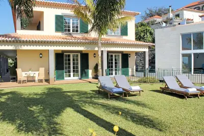 a yard with lounge chairs and a house at Magnificent Funchal Villa Villa Luzia 5 Bedrooms Sea & City Views in Funchal