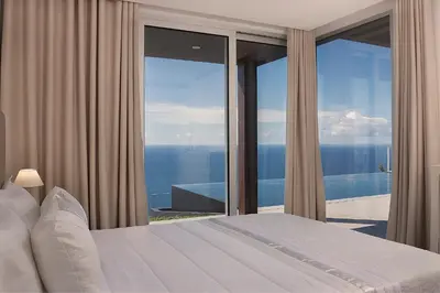 a bedroom with a bed and a view of the ocean at Spectacular Calheta Villa Villa Cliffscape 3 Bedrooms Panoramic Sea View in Estreito da Calheta
