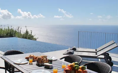 a table with fruit on it next to a swimming pool at Spectacular Calheta Villa Villa Cliffscape 3 Bedrooms Panoramic Sea View in Estreito da Calheta