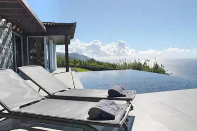 a pair of lounge chairs on a patio next to a swimming pool at Spectacular Calheta Villa Villa Cliffscape 3 Bedrooms Panoramic Sea View in Estreito da Calheta