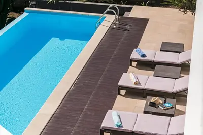 an overhead view of a swimming pool with chaise lounge chairs and a swimming pool at Extravagant Calheta Villa The Designhouse 4 Bedrooms Stunning Sea Views in Arco da Calheta