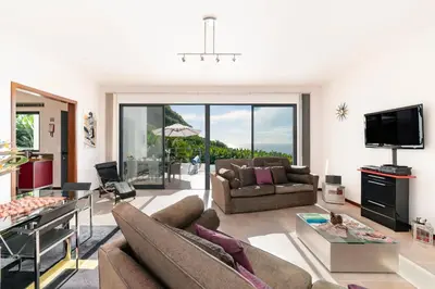 a living room with a couch and a tv at Extravagant Calheta Villa The Designhouse 4 Bedrooms Stunning Sea Views in Arco da Calheta