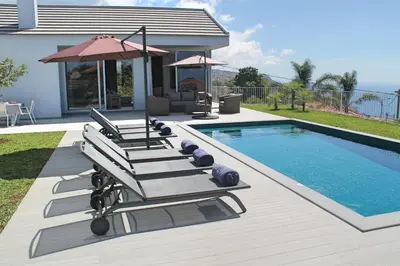 a group of lounge chairs next to a swimming pool at Luxury Calheta Villa Casa Calheta Heights 3 Bedrooms Stunning Sea Views in Calheta