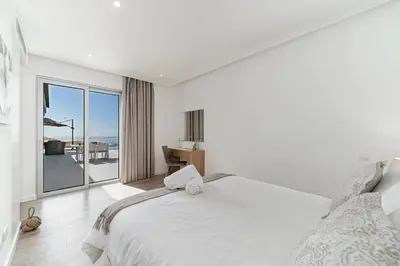 a white bedroom with a bed and a view of the ocean at Luxury Calheta Villa Casa Calheta Heights 3 Bedrooms Stunning Sea Views in Calheta