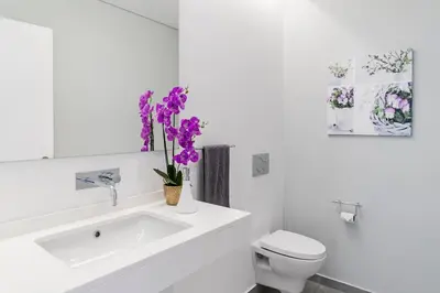 a bathroom with a sink and a toilet and purple flowers at Luxury Calheta Villa Casa Calheta Heights 3 Bedrooms Stunning Sea Views in Calheta