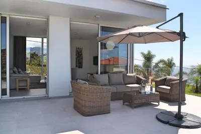 a patio with a couch and an umbrella at Luxury Calheta Villa Casa Calheta Heights 3 Bedrooms Stunning Sea Views in Calheta