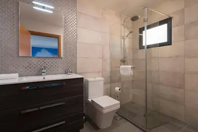 a bathroom with a toilet and a glass shower at Luxury Calheta Villa Casa Da Rosalina 5 Bedrooms Stunning Sea Views in Calheta