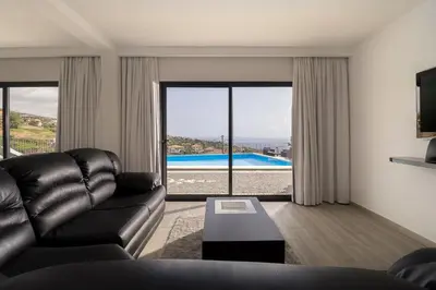 a living room with a leather couch and a view of a pool at Luxury Calheta Villa Casa Da Rosalina 5 Bedrooms Stunning Sea Views in Calheta