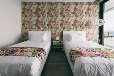 two beds in a room with a floral wallpaper at Villa Brava Atlântico in Ribeira Brava