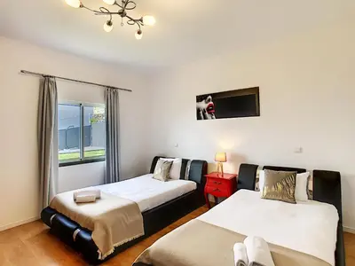 a bedroom with two beds and a tv on the wall at Villa Prainha by LovelyStay in Caniçal