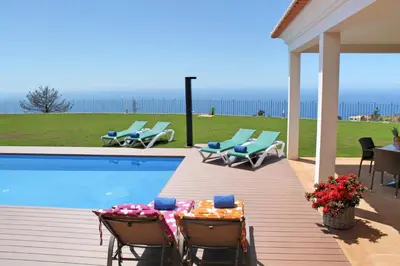 a patio with a table and chairs next to a swimming pool at Bellevue Villa Madeira Magnificent Sea View in Prazeres