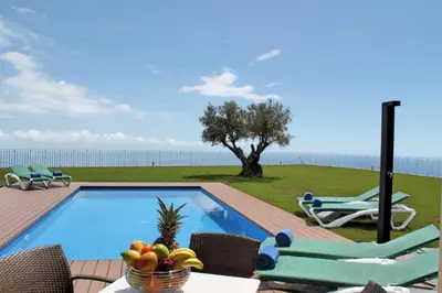 a swimming pool with chairs and a table with a bowl of fruit at Bellevue Villa Madeira Magnificent Sea View in Prazeres