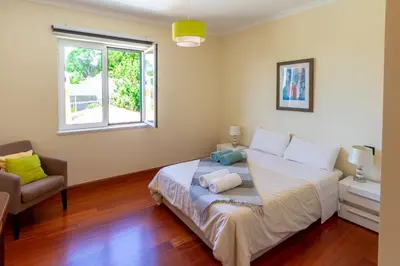 a bedroom with a bed and a chair and a window at Bellevue Villa Madeira Magnificent Sea View in Prazeres