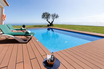a swimming pool on a wooden deck with a chair next to it at Bellevue Villa Madeira Magnificent Sea View in Prazeres