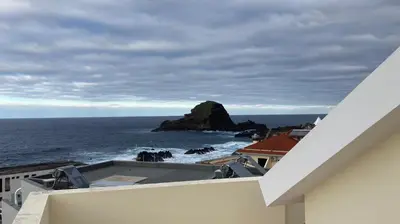 a view of a rock in the ocean from a building at Costa Azul in Porto Moniz