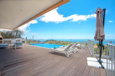 a deck with chairs and an umbrella and a pool at Casa Luz by LovelyStay in Prazeres