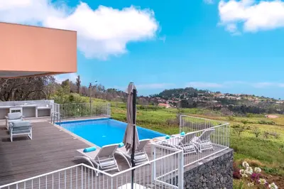 a pool with chairs and an umbrella on a deck at Casa Luz by LovelyStay in Prazeres
