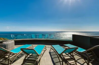 a group of chairs and tables on a balcony with the ocean at Villa Belmonte by LovelyStay in Ponta do Sol