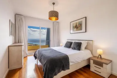 a bedroom with a bed and a large window at Sea View by Atlantic Holiday in Caniço