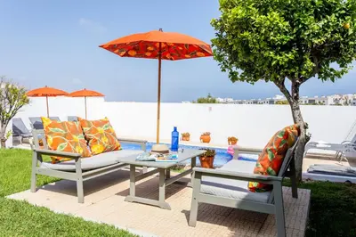 a patio with two chairs and a table with an umbrella at CoolHouses Algarve Lagos, V3 Casa Evasion in Lagos